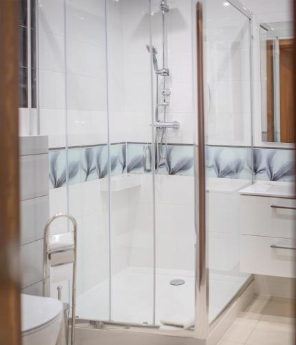 a shower with a glass door in a bathroom at Pod Wzgórzem Bed & Breakfast in Frombork