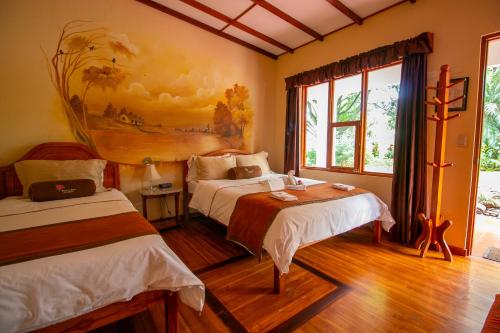 ein Schlafzimmer mit 2 Betten und einem Wandgemälde in der Unterkunft Hotel La Rosa de America in Alajuela