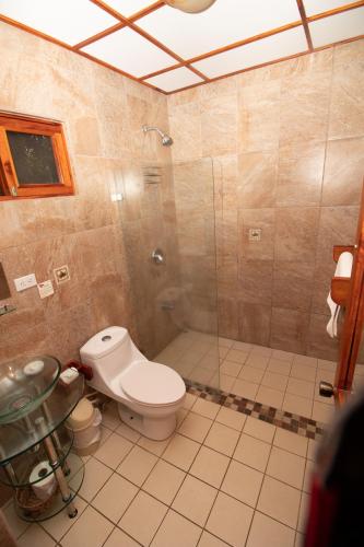 a bathroom with a toilet and a glass shower at Hotel La Rosa de America in Alajuela City
