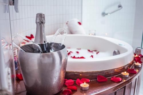 Real Classic Hotel في أراكاجو: حمام مع حوض مع زجاجة من الشمبانيا والورود الحمراء