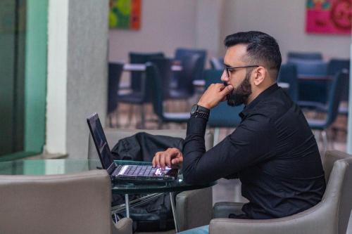 a man sitting at a table using a laptop computer at Real Classic Hotel in Aracaju