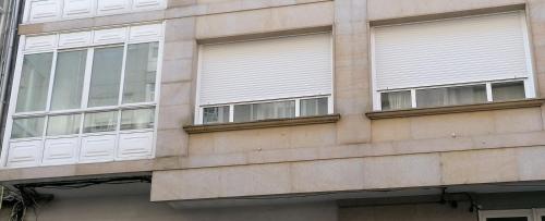 ポンテベドラにあるAPARTAMENTO BOLBORETAの窓と白いブラインドが付いた建物