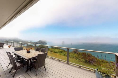 a table and chairs on a deck with a view of the ocean at Whalerock Luxury Home in Trinidad