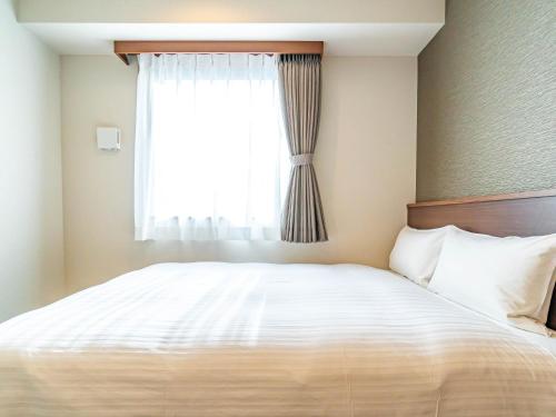 a bedroom with a large bed with a window at Bande Hotel Tenpozan Higashi in Osaka