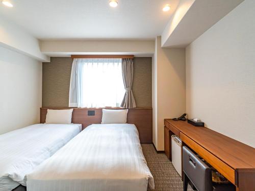 a hotel room with two beds and a window at Bande Hotel Tenpozan Higashi in Osaka