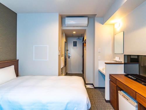 a hotel room with a bed and a bathroom at Bande Hotel Tenpozan Higashi in Osaka