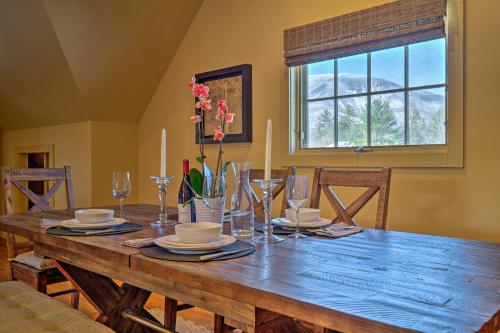 a wooden table with plates and glasses and a window at Luxe Green Barn Near Skiing with Mt Equinox Views! in Manchester Center