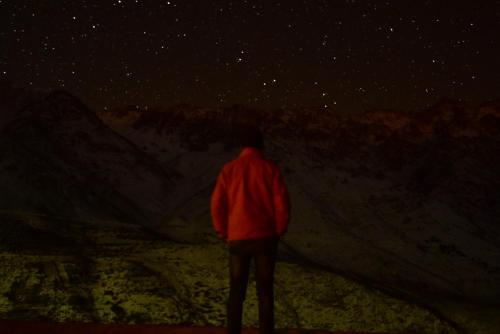a man in a red jacket looking at the stars at Gite Angour Tacheddirt in Tacheddirt
