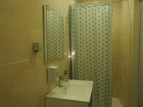 une salle de bain avec un lavabo et une douche avec un miroir dans l'établissement Happen!ng, à Faro