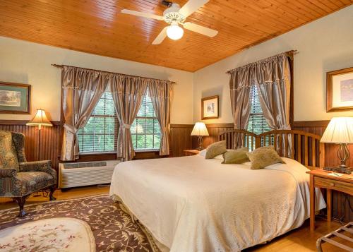 a bedroom with a large bed and two windows at Highland Lake Inn & Resort - Flat Rock in Flat Rock