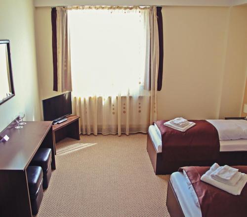 a hotel room with two beds and a desk and a window at Cazare Karmina in Baia Mare