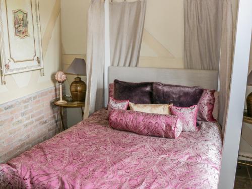 a pink bed with purple sheets and pillows on it at Swiss Cottage in Mohill