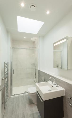 a bathroom with a shower and a sink and a toilet at 2 Woolacombe West - Luxury Apartment at Byron Woolacombe, only 4 minute walk to Woolacombe Beach! in Woolacombe