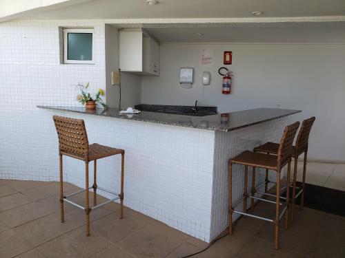 a kitchen with two bar stools and a counter top at Flet Beira-mar, Blue Sucet in João Pessoa