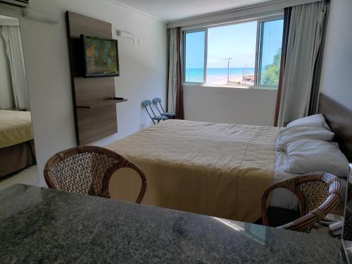 a hotel room with a bed and a table and chairs at Flet Beira-mar, Blue Sucet in João Pessoa