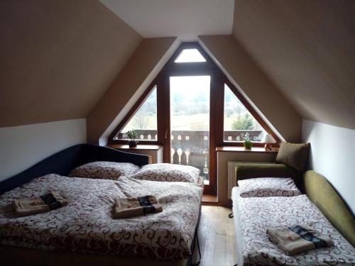 a attic bedroom with two beds and a window at Ubytovanie na briežku in Mlynky 