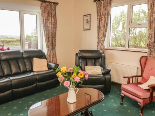 a living room with a couch and a table with flowers at Cleary Cottage in Miltown Malbay