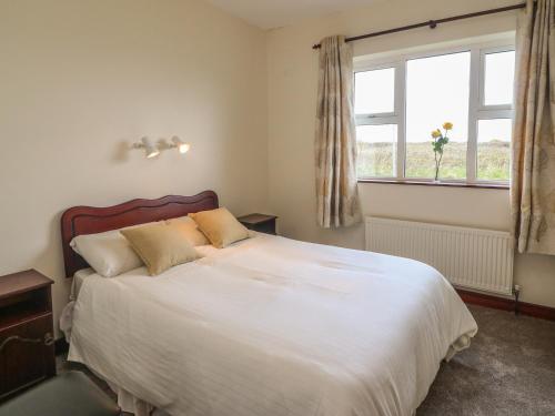 a bedroom with a large white bed with a window at Cleary Cottage in Miltown Malbay