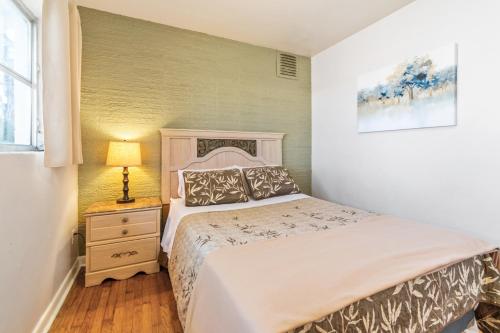 a bedroom with a bed and a nightstand with a lamp at Mid-century Home 2 miles to UF, Downtown, and Shands Plus Walk to Coffee Culture, Planet Fitness and Alfred A Ring Park in Gainesville