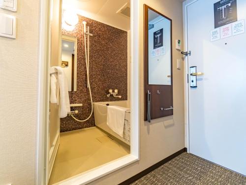 a bathroom with a tub and a shower with a mirror at Bande Hotel Tenpozan Higashi in Osaka