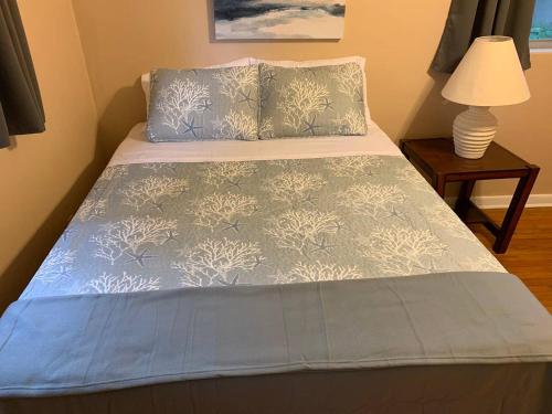 a bed with a blue comforter and two pillows at Mid-century Home 2 miles to UF, Downtown, and Shands Plus Walk to Coffee Culture, Planet Fitness and Alfred A Ring Park in Gainesville