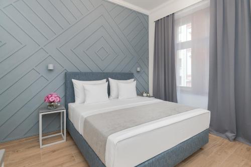 a bedroom with a white bed and a blue wall at Eight Secrets Boutique Residence by Dwellfort in Prague