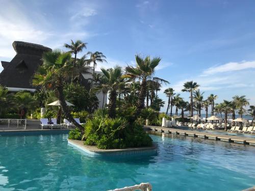 a pool at a resort with palm trees and chairs at Villa dentro del Hotel Vidanta Mayan Palace in Acapulco