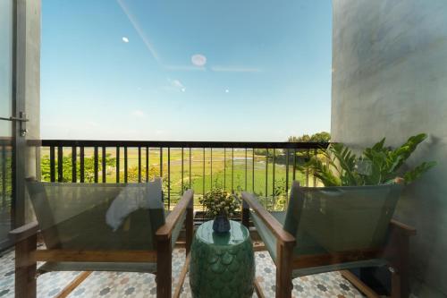two chairs and a table on a balcony with a view at Paddy Boutique House Hoian in Hoi An