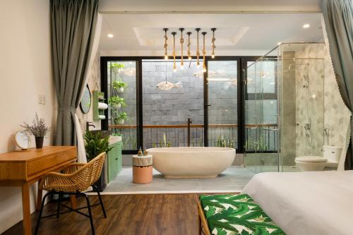 a bedroom with a tub and a bed and a desk at Paddy Boutique House Hoian in Hoi An