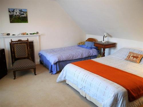 a bedroom with two beds and a chair and a desk at Mackenzie House in Kirkcudbright