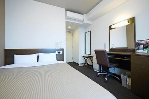 a hotel room with a bed and a desk and a mirror at Hotel Route-Inn Yurihonjo in Yurihonjo