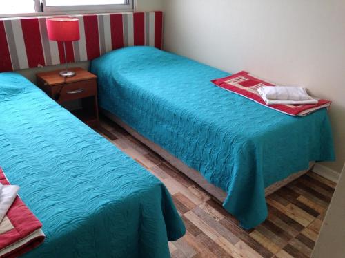 2 camas en una habitación con sábanas azules y una mesa en Departamento Av. del Mar de Coquimbo, en Coquimbo