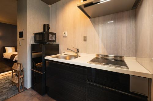 a small kitchen with a sink and a microwave at GRAND BASE Haruyoshi in Fukuoka