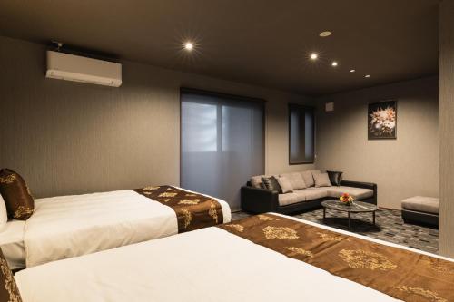 um quarto de hotel com duas camas e um sofá em GRAND BASE Haruyoshi em Fukuoka