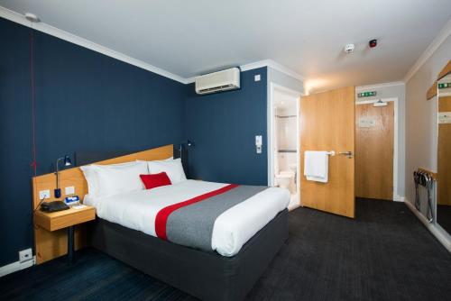 a bedroom with a large bed and a blue wall at Holiday Inn Express Derby Pride Park, an IHG Hotel in Derby