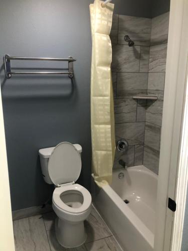 a bathroom with a toilet and a shower and a tub at EVERKLEEN Motel Downtown in San Antonio