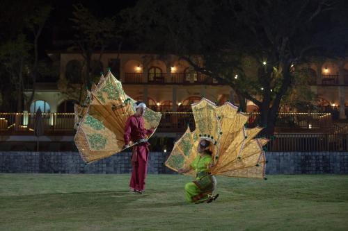 two people are holding umbrellas in a field at Sanctum Inle Resort in Nyaung Shwe