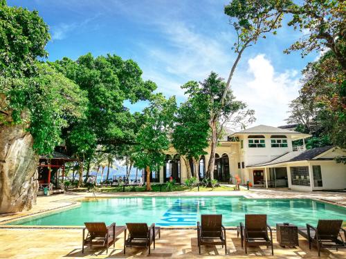 a swimming pool with chairs and a house at Matinloc Island Resort in El Nido