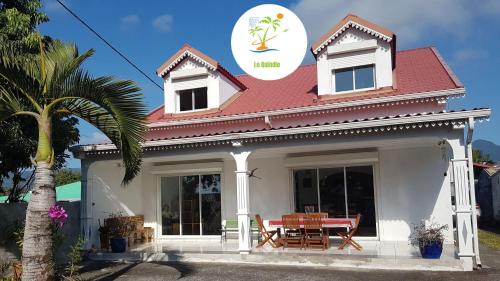 a white house with a red roof and a table at Le Quindio in Bras-Panon