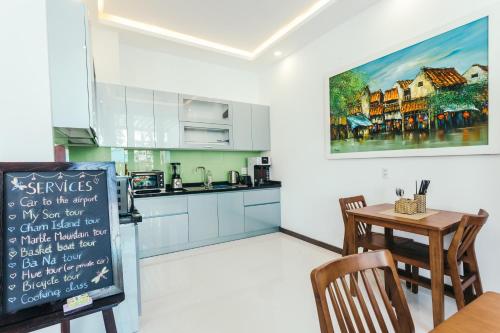 eine Küche mit weißen Schränken, einem Tisch und einem Schild in der Unterkunft Le Petit Villa Hoi An in Hoi An