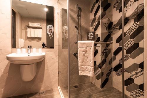 a bathroom with a sink and a glass shower at Fish Hotel Kaohsiung in Kaohsiung