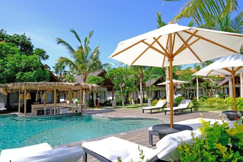 a pool with chairs and umbrellas in a resort at Kashantee Village in Seminyak
