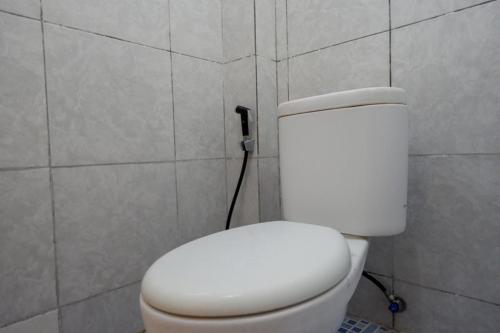 ein Bad mit einem weißen WC in einer Wand in der Unterkunft RedDoorz Syariah @ Hotel Wisma Indonesia Kendari in Kendari