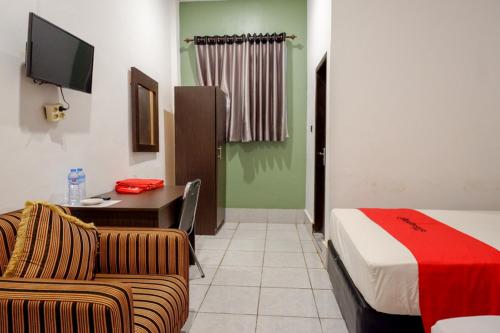 a room with a couch and a bed and a desk at RedDoorz Syariah @ Hotel Wisma Indonesia Kendari in Kendari