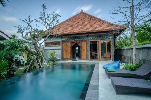 a swimming pool in front of a house at Fins Villa Medewi in Airsatang