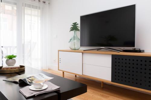 a living room with a large television on a white cabinet at Tauro 195 near El Corte Ingles in Lisbon