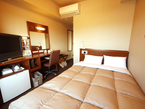 una camera d'albergo con un grande letto e una scrivania di Hotel Route-Inn Gotenba Eki-Minami a Gotemba