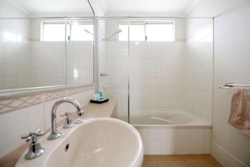 a white bathroom with a sink and a tub at Wavecrest Village & Tourist Park in Hopetoun