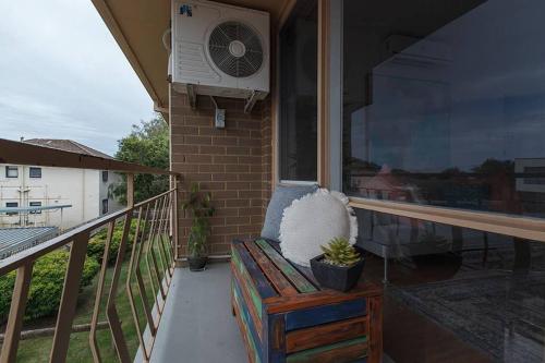 a porch with a bench and a fan on a balcony at Heart of Ormond Apartment by Ready Set Host in Carnegie