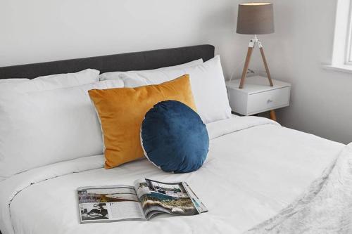 a bed with a pillow and a magazine on it at Heart of Ormond Apartment by Ready Set Host in Carnegie